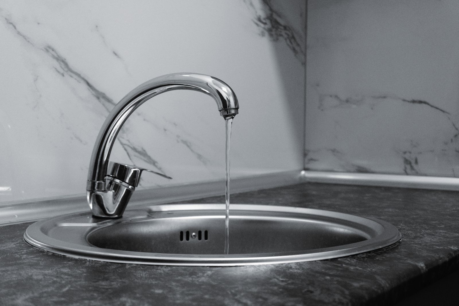 Kitchen faucet running clear into a stainless steel sink