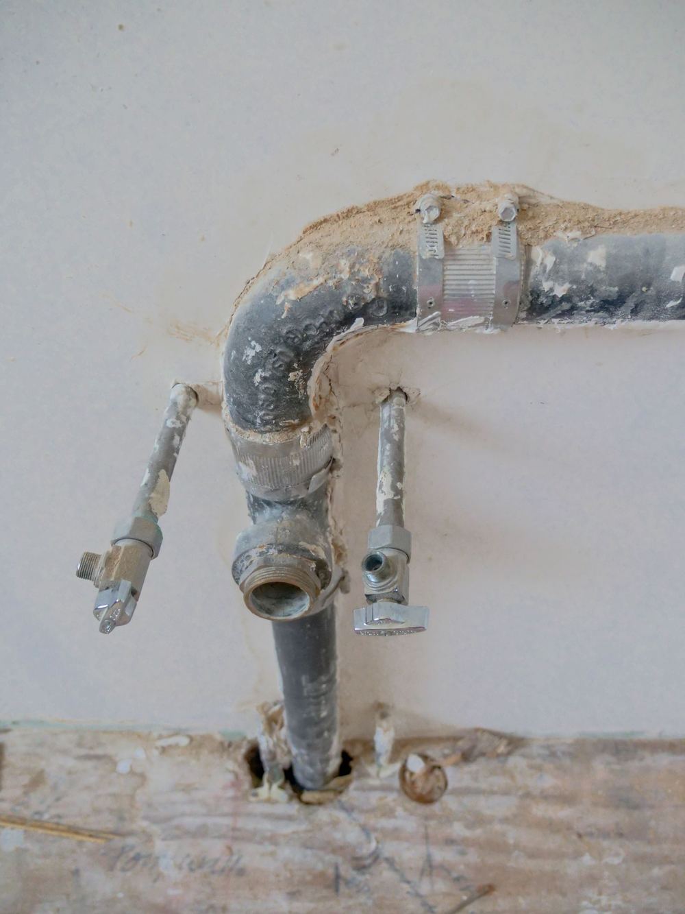 Original cast-iron drain pipes and shutoff valves in an older Newport Beach home