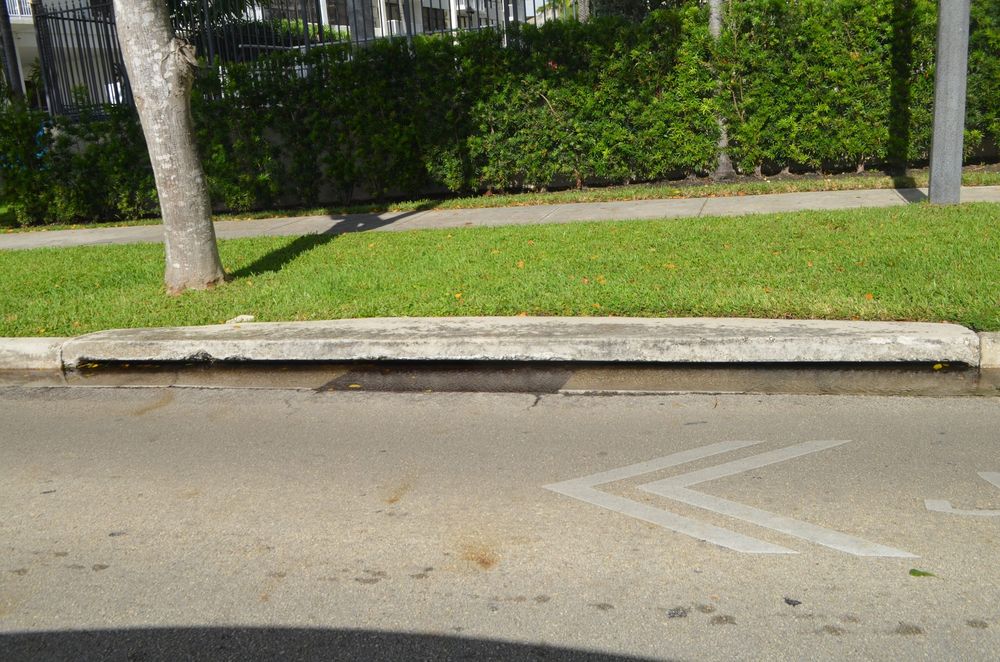 Street drain at the curb as king-tide water reaches the roadway
